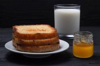 Süt ile bir tabakta tost ve bir kutu tatlım. Siyah bir ahşap arka plan üzerinde