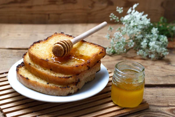 Ahşap arka plan üzerinde bal ile üç kızarmış tost