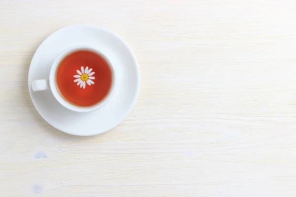 Tee in einem weißen Kruschke auf einer Untertasse mit Kamille und legen Sie unter den Text — Stockfoto