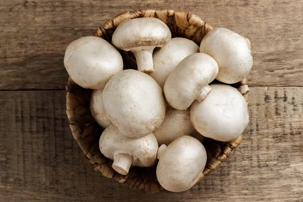 Ahşap arka plan üzerinde bir hasır sepet içinde mantar petrol