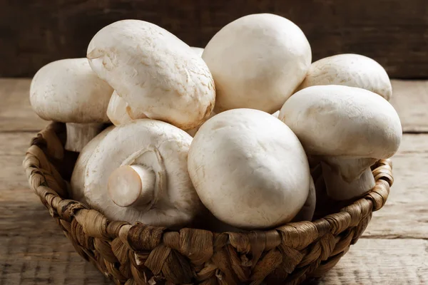 Ahşap arka plan üzerinde bir hasır sepet içinde mantar petrol