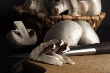 Bir kesme tahtası ve bıçak ile bir hasır sepet içinde mantar petrol