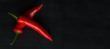 Karanlık bir arka plan üzerinde kırmızı acı biber. Metnin altında bir yer ile geniş bir görüntü