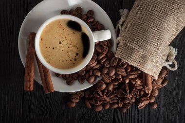 Köpük anason ve tarçın kahve taneleri arasında bir fincan taze kokulu kahve