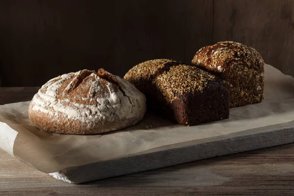 Kağıt ve ahşap arka plan yuvarlak ve siyah çavdar ekmek — Stok fotoğraf