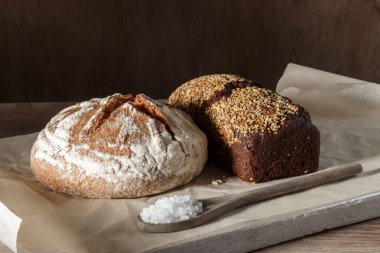 Yuvarlak ve çavdar ekmek tuz ahşap arka plan üzerinde siyah