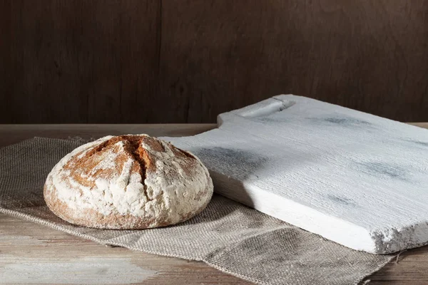 Στρογγυλή σιτάρι ψωμί σικάλεως με λευκό του σκάφους στην απόλυση σε φόντο ξύλινη — Φωτογραφία Αρχείου