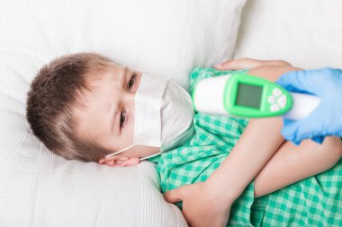 Hasta çocuk ısıyı termometreyle ölçüyor.