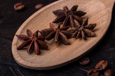 Anis, tahta bir kaşıkta, beton bir arka planda, kahve taneleriyle.