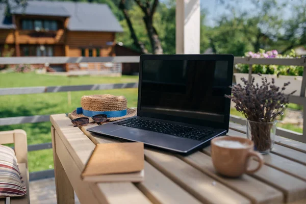 Workplace in summer in the country. Laptop and notepad lie on the table