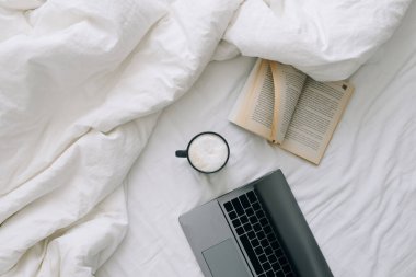 Evden çalışıyorum. Laptop ve fincanla birlikte kahve ve kitap. Üst görünüm