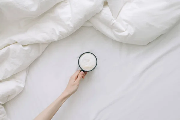 Mão Feminina Segura Xícara Café Sobre Cama Espalhada Vista Superior — Fotografia de Stock