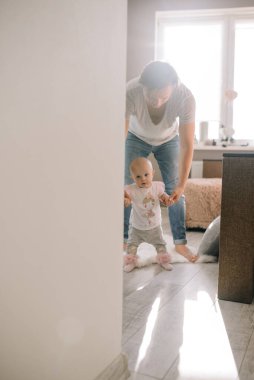 Babacık küçük bebeğe yürümeyi öğretiyor. Küçük bebek babasının elini tutuyor. Deniz fenerinde ilk adımı atıyor..