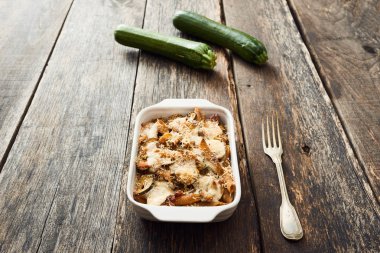 Fırında makarna pişirme çanağı ve eski ahşap masa, kabak arka planda beyaz kabak ile