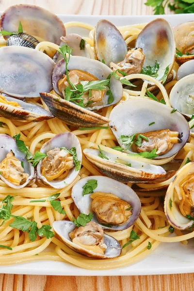 Beyaz kare tabak üzerinde buğulanmış midye makarna