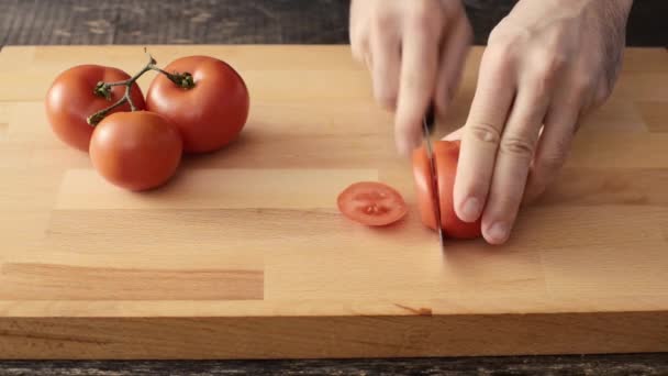 Männliche Hand schneidet Tomaten auf Holzschneidebrett — Stockvideo