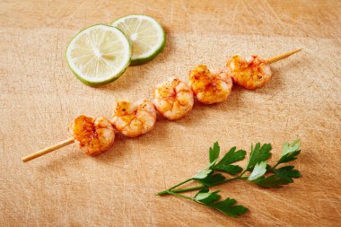 Karides şiş limon dilimleri ve maydanoz kesme tahtası üzerinde