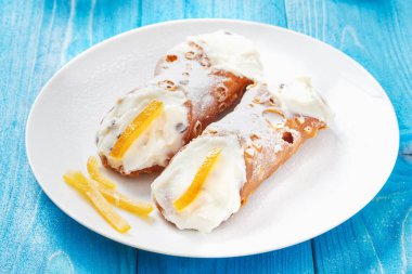 Sicilya Cannoli beyaz tabak mavi ahşap masa üzerinde üzerinde