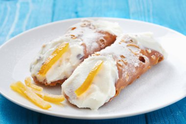 Yakın çekim Sicilya Cannoli beyaz tabak mavi ahşap masa üzerinde üzerinde