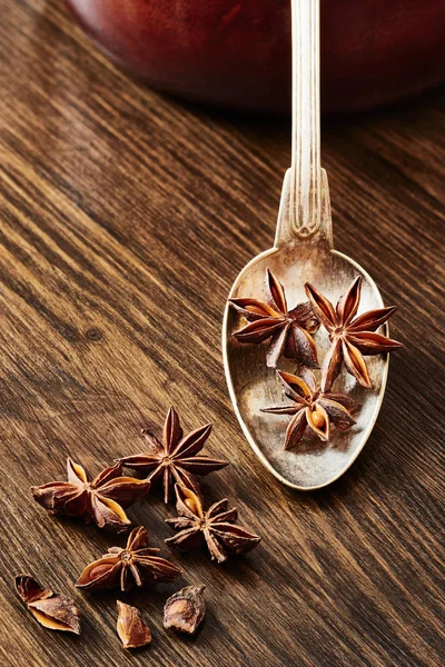 Star anise on old spoon surrounded by star anise on wooden table