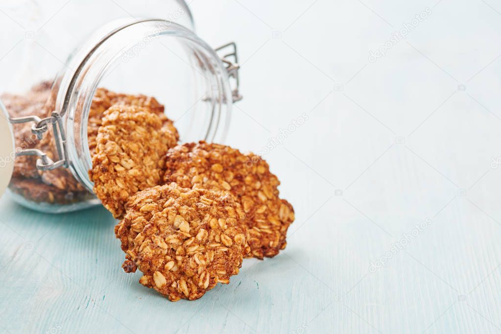 Oatmeal banana cookies out of a jar on blue table - text space on the right