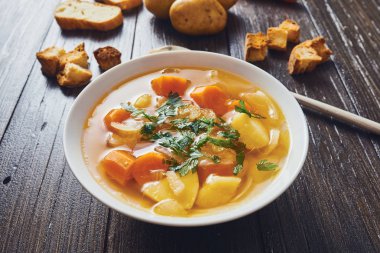 İngradients ahşap masa üzerinde çevrili beyaz kase sebze çorbası