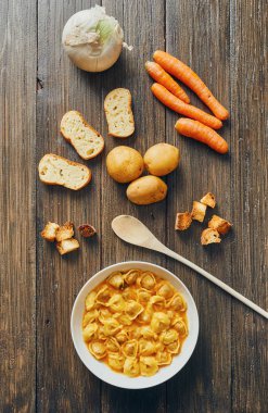 Ahşap masa üzerinde beyaz tabak tortellini çorbası