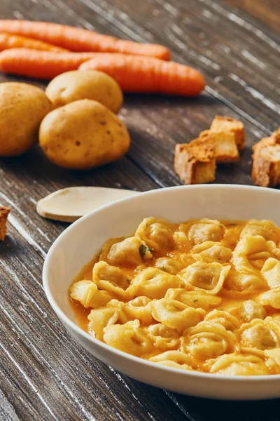 Sopa de tortellini em prato branco em mesa de madeira — Fotografia de Stock