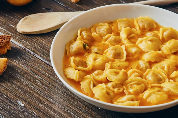 Ahşap masa üzerinde beyaz tabak tortellini çorbası