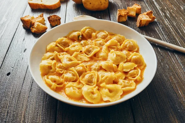 Sopa de tortellini em prato branco em mesa de madeira — Fotografia de Stock