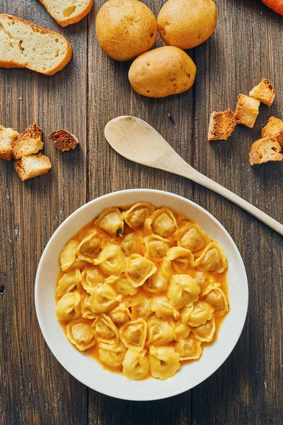 Sopa de tortellini em prato branco em mesa de madeira — Fotografia de Stock