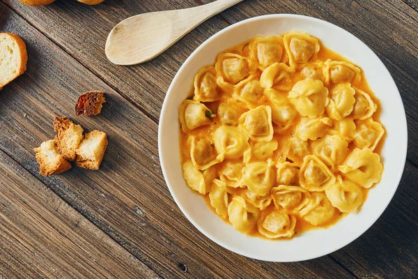 Ahşap masa üzerinde beyaz tabak tortellini çorbası