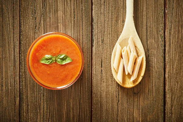 Деревянная ложка с сырой пастой и домашним томатным соусом на деревянном столе Стоковая Картинка