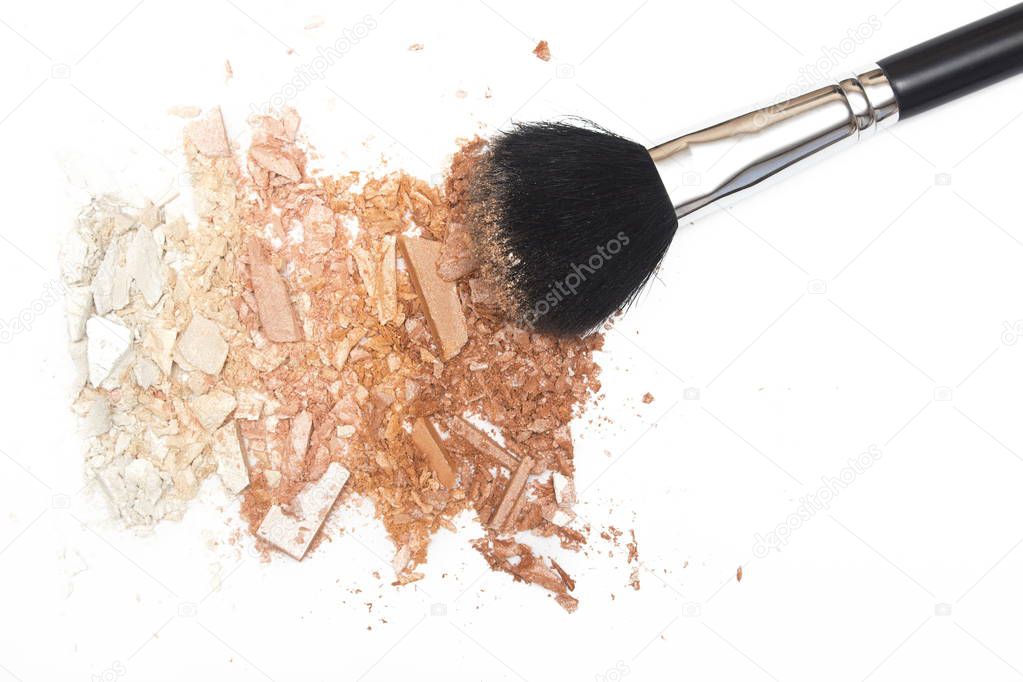 Crushed powder and powder brush on white background
