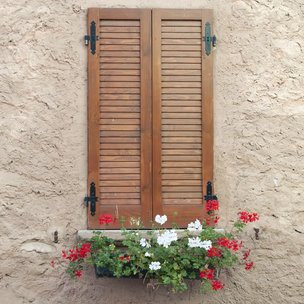 Fönster med stängda luckor och blommor — Stockfoto