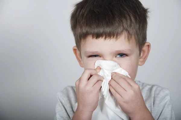 sick child blows his nose in a handkerchief