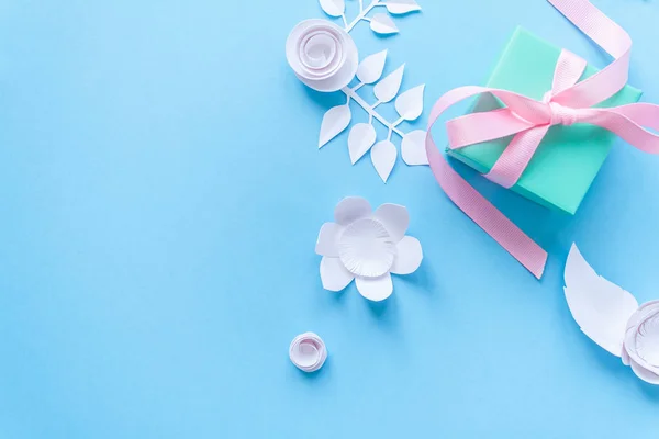 Un regalo y flores de papel blanco sobre fondo azul — Foto de Stock