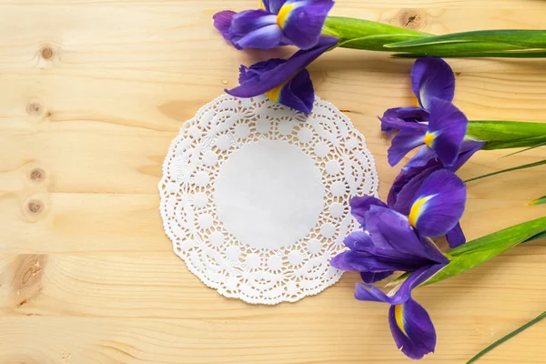 Hadiah pada serbet putih dan tiga iris pada latar belakang kayu — Stok Foto