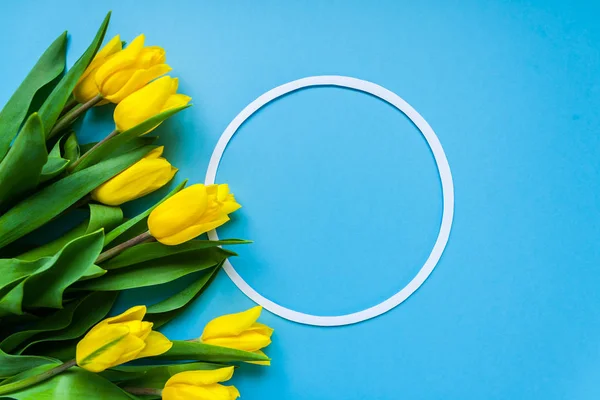 Cornice rotonda e tulipani gialli su sfondo blu — Foto Stock