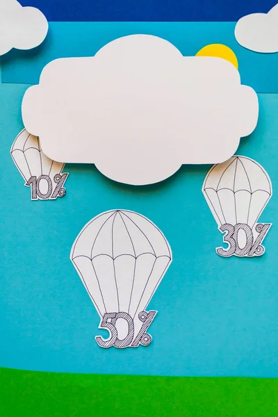 Concept of modern sale. Sky, clouds, parachutes, discounts cut from paper.