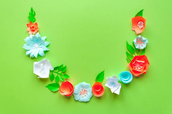 frame with color paper flowers on the green background. Flat lay. Nature concept