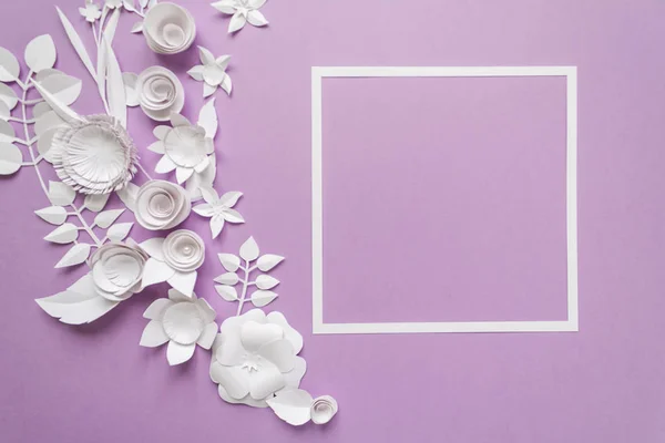 用白色纸花紫罗兰色背景上的方框。由纸剪成. — 图库照片