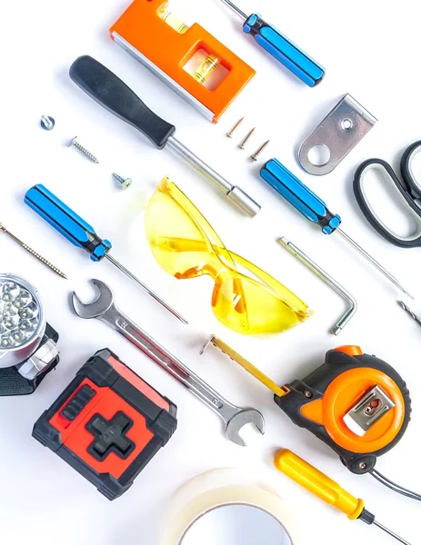 Top view of working tools, wrench, screwdriver, level, tape measure, bolts, and safety glasses on a white background. — Stock Photo, Image