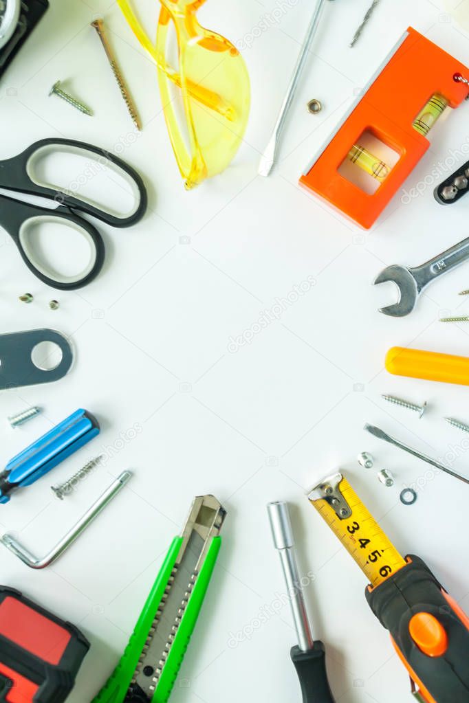 Top view of working tools, wrench, screwdriver, level, tape measure, bolts, and safety glasses on a white background.