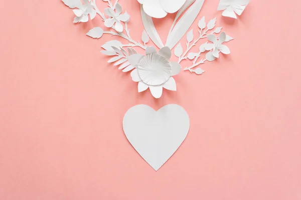heart out of paper flowers cut from paper on pink background