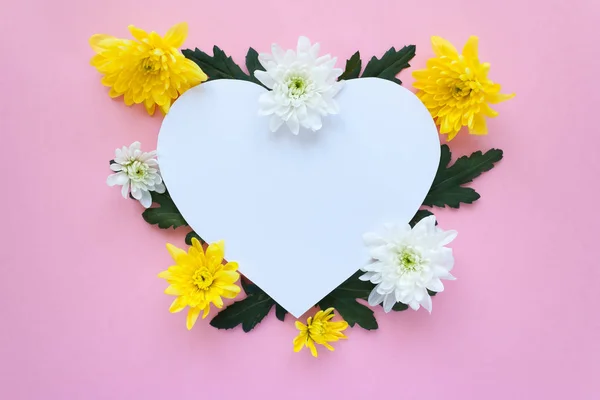 Heart frame. white and yellow chrysanthemums on a pale pink background