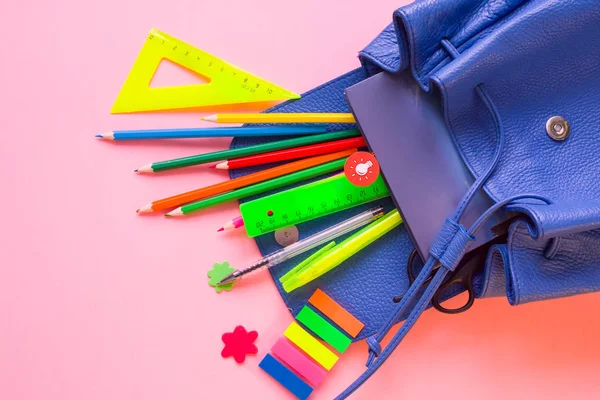 蓝色背包与学校供应在粉红色背景 — 图库照片