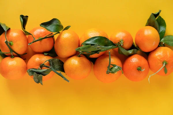 Πορτοκαλί μανταρίνι με φύλλα σε κίτρινο φόντο — Φωτογραφία Αρχείου