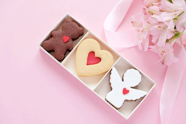 Sušenky ve tvaru anděla, srdce, medvěd s růžovou stuhou s lisianty na růžovém pozadí. — Stock fotografie