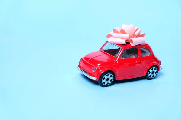 O carro vermelho está amarrado com um laço de presente. O conceito de um presente . — Fotografia de Stock